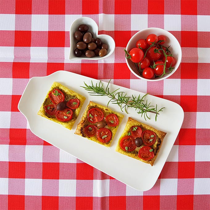 Pizzette vegane con pomodorini, olive, pesto ed erbe aromatiche